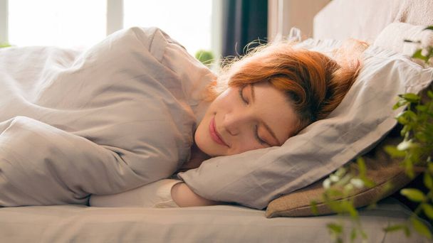 Caucasian happy woman sleeping in comfortable cozy bed at home girl lady asleep lying on soft pillow white linen orthopedic mattress resting relaxing napping healthy sleep nap in morning stress relief - Fotografie, Obrázek