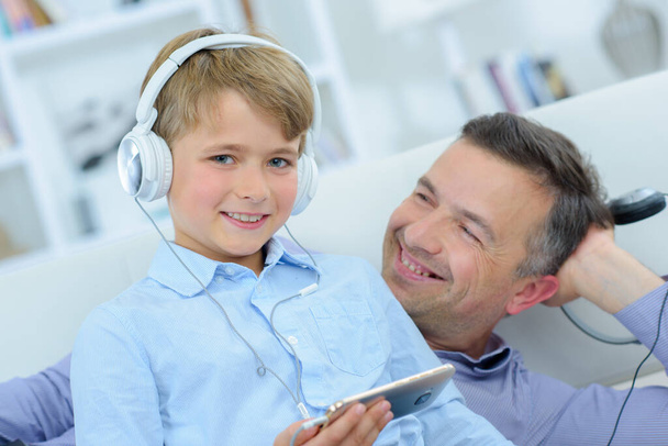 Portrait of child with father, wearing headphones - Foto, imagen
