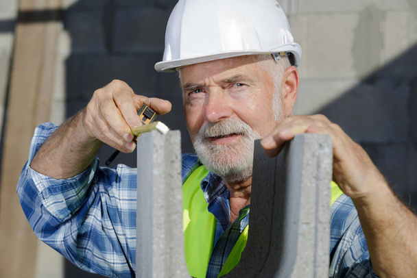 elderly man working around a concrete wall - Фото, зображення