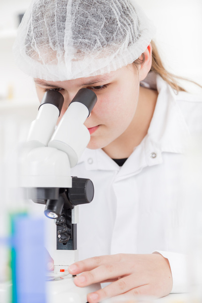 Woman scientist working with a microscope in a lab - Фото, зображення