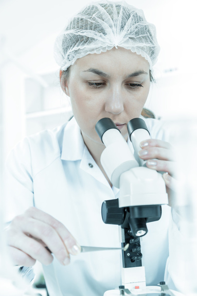Γυναίκα επιστήμονας που εργάζεται με ένα μικροσκόπιο σε ένα εργαστήριο - Φωτογραφία, εικόνα