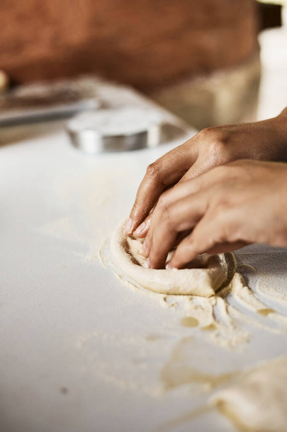 Hands knead dough to make a pizza, selective focus - Foto, afbeelding