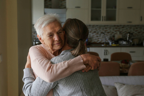 Geriatric social worker helping an elderly woman to get up. Senior sitter and old age lady hugging. Close up, copy space, background. - Foto, Bild