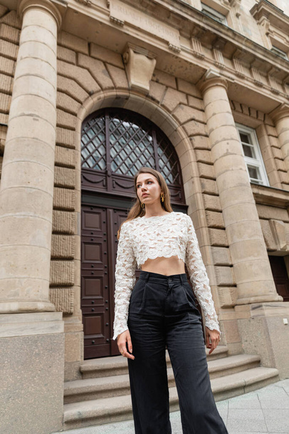 elegantní mladá žena v krajky horní a vysoký pas kalhoty odvrací pohled na městské ulici v Berlíně - Fotografie, Obrázek
