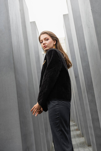 Portrait of young woman in jacket looking at camera between Memorial to Murdered Jews of Europe - Photo, Image