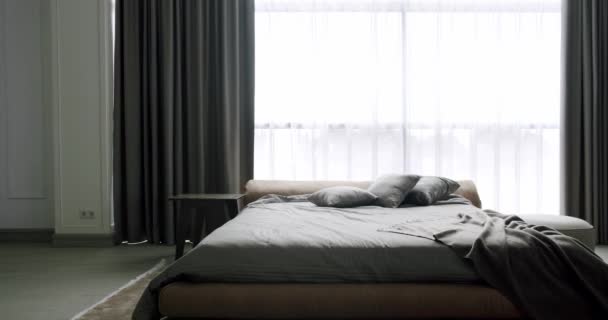 Modern Hotel Bedroom Interior and bed with many pillows. Minimalistic scandinavian style of interior. Elegant and Simple Bedroom With a King Sized Bed. Interior with shelves on white wall. - Footage, Video