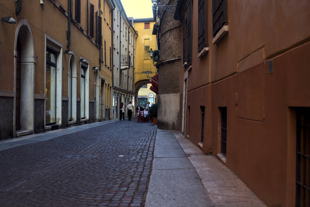Calle estrecha y empedrada a la sombra con gente paseando por una ciudad italiana al atardecer - Foto, imagen