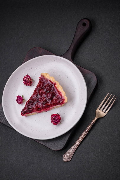 Вкусный ароматный сладкий пирог с ягодами вишни на керамической пластине на темном бетонном фоне - Фото, изображение