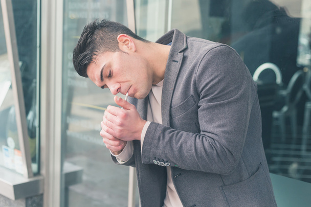 Young handsome man smoking a cigarette - 写真・画像