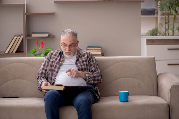 Ο γέρος διαβάζει βιβλία στο σπίτι κατά τη διάρκεια πανδημίας - Φωτογραφία, εικόνα