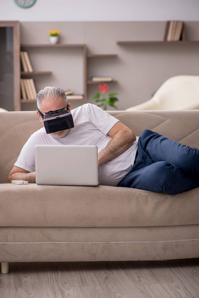 Hombre envejecido disfrutando de gafas virtuales en casa - Foto, imagen