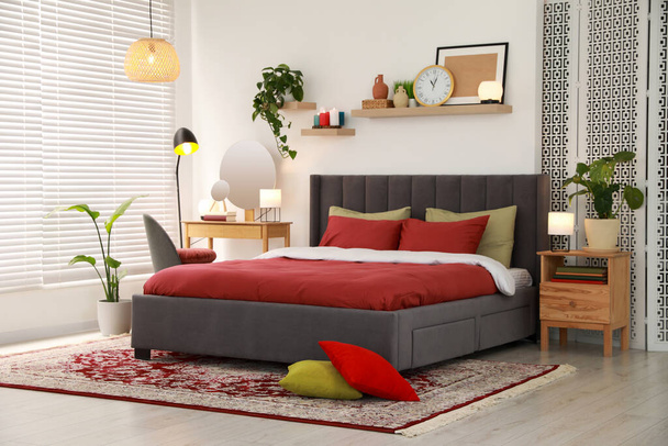 Stylish bedroom interior with comfortable bed and green houseplants - Фото, зображення