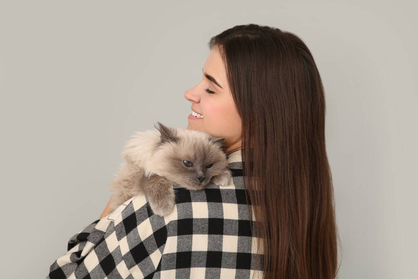 Woman with her cute cat on light grey background - Fotoğraf, Görsel