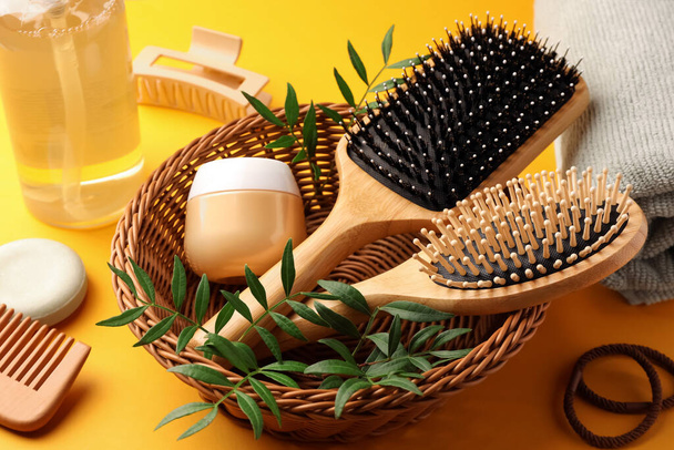 Wooden brushes and different hair products on orange background - Photo, Image