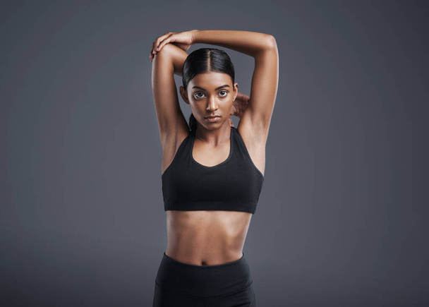 Portrait, mockup and stretching with a sports woman in studio on a gray background for fitness or health. Exercise, workout and warm up with an attractive young female athlete training her body. - 写真・画像