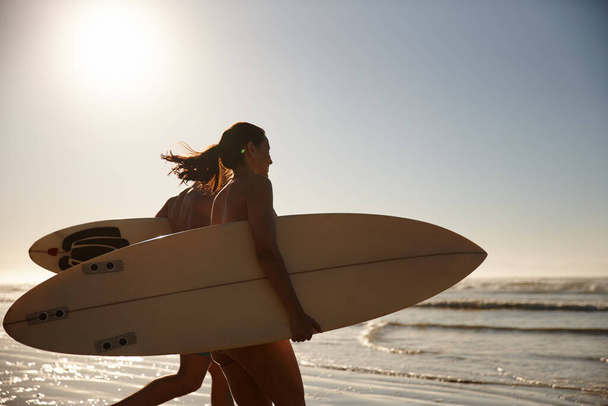Fare surf insieme. una giovane coppia di surfisti che corre verso le onde - Foto, immagini
