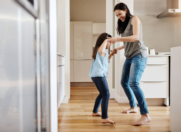 Holding hands, dance and a child with a mother in the kitchen, bonding and quality time together. Smile, laughing and a mom teaching her daughter with dancing, love and happiness with fun in a house. - Photo, Image