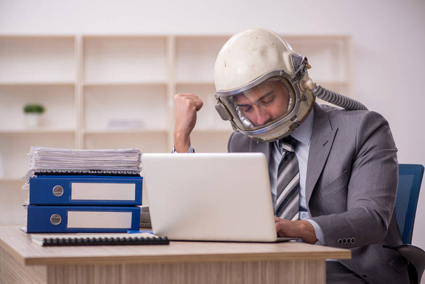 Young businessman employee wearing spacesuit at workplace - Fotó, kép