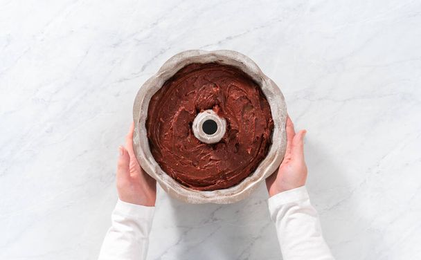 Επίπεδη. Γεμίζοντας μεταλλικό ταψί με βούτυρο κέικ για να ψήσετε κόκκινο βελούδινο bundt κέικ με κρέμα τυριού - Φωτογραφία, εικόνα