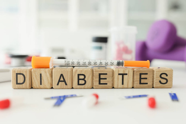 Word Diabetes made with wooden cubes and syringe on table. Chronic endocrine disease caused by sustained high blood sugar levels. Insulin shot - Foto, afbeelding