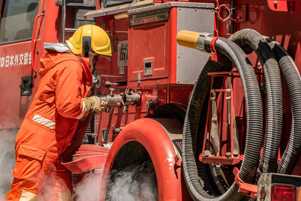 Les années d'expérience des pompiers brillent alors qu'il relie le tuyau à la bouche d'incendie en utilisant leur expertise pour maximiser le débit d'eau et l'énergie d'extinction. - Photo, image