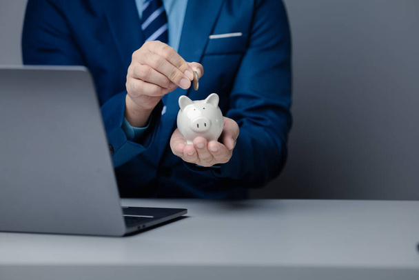 A person is holding a piggy bank, saving money and managing personal finances. Concept of increasing savings and savings by investing in stock mutual funds. - Foto, afbeelding