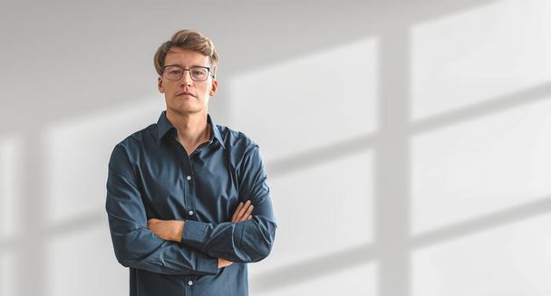 Serious businessman in blue shirt, looking at the camera, arms crossed on empty copy space white shadow background. Concept of business plan, idea and development - Zdjęcie, obraz