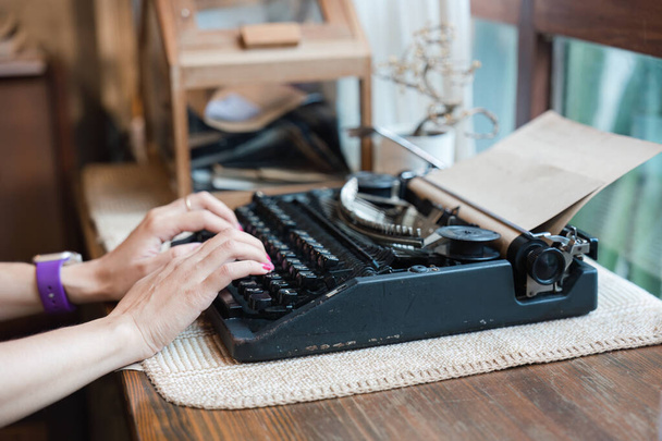 Kéz a nő gépelés régi vintage írógépen papírral a fa íróasztalon - Fotó, kép