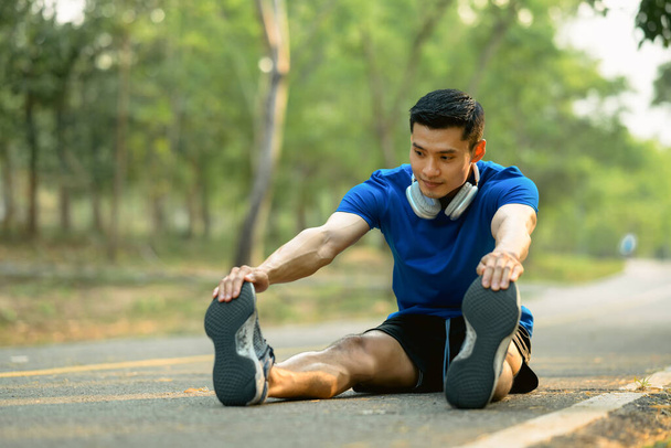 Een atletische man die zijn spieren uitrekt voor hij 's morgens wegloopt. Fitness, sport en een gezonde levensstijl. - Foto, afbeelding