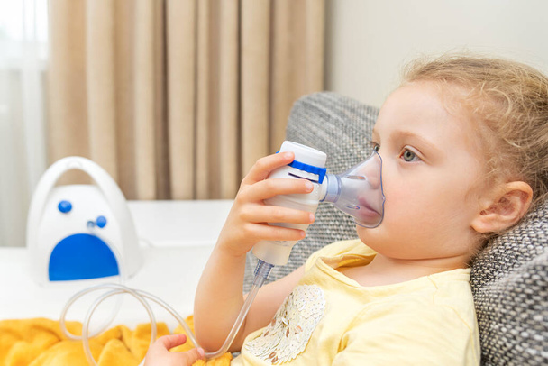 Het kind ademt via een inhalator. Behandeling van verkoudheid en allergieën. - Foto, afbeelding