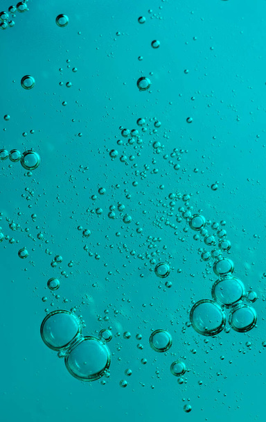 air bubbles on beautiful blue and blue cosmetic serum background for advertising and presentation of cosmetic products. Macro photo, vertical - Photo, Image