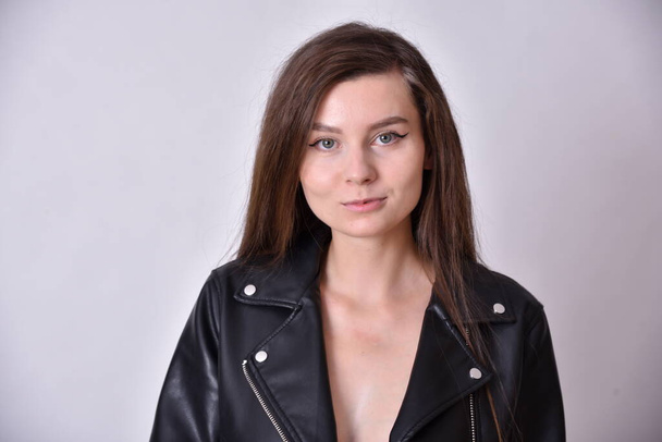 Young woman, brunette. Female model with black leather jacket. Studio photo with white background. - Photo, Image
