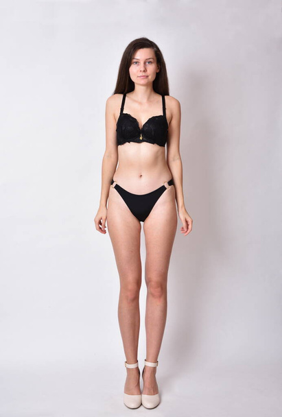 Young woman, brunette. Female model with black underwear, profile photo shoot. - Фото, зображення