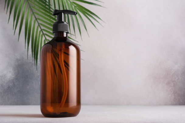 Recycled plastic pump bottle for mock-up with palm leaves. Spa and wellness concept, minimalism brand packaging mock-up. - Fotó, kép