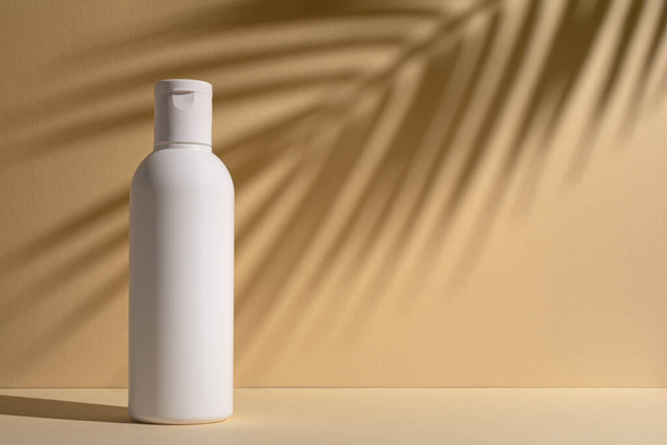 White blank packaging cosmetic plastic bottle with shadow of palm leaves. Spa and grooming product.  - 写真・画像