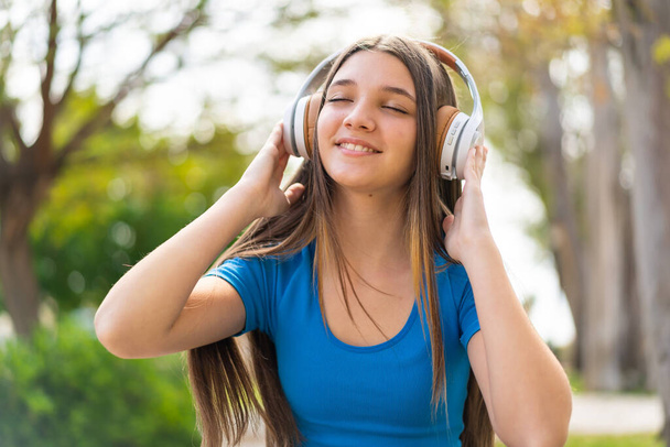 Дівчина-підліток на відкритому повітрі слухає музику
 - Фото, зображення