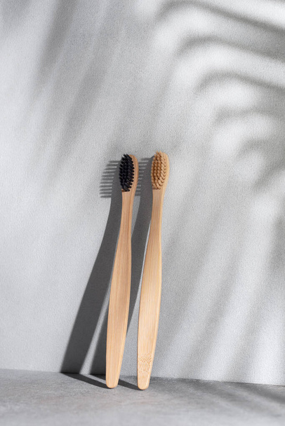 Eco friendly bamboo toothbrushes with shadow of palm leaf on background. Zero waste and plastic free product lifestile. - Fotó, kép