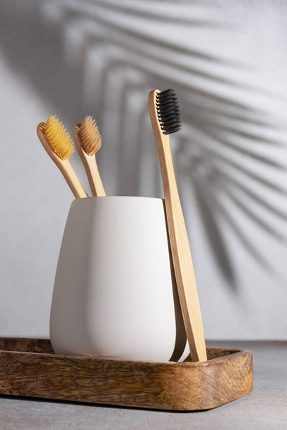 Eco friendly bamboo toothbrushes with shadow of palm leaf on background. Zero waste and plastic free product lifestile. - Foto, Imagen