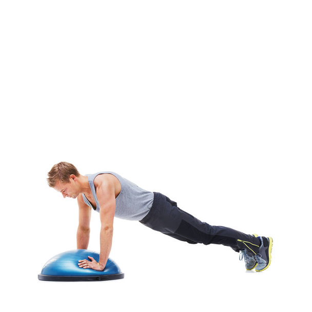 His workout plan is simple but effective. A young man doing push-ups on a bosu-ball - Фото, изображение