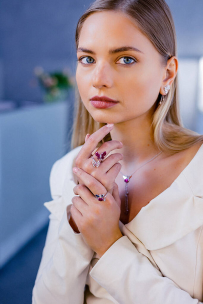 Portrait of a beautiful girl with diamonds in a jewelry salon. The girls face has a flawless shine, and the model is adorned with a diamond necklace and earrings - Фото, зображення
