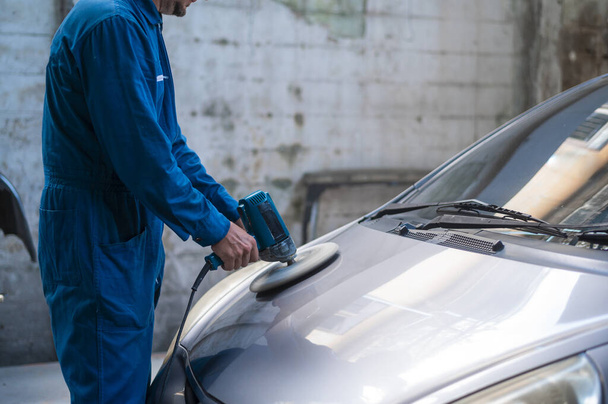 Close-up  man hand is using car polishing machine in repair mechanic painting shop  - Φωτογραφία, εικόνα