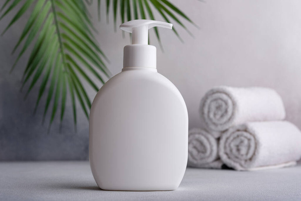 White blank packaging cosmetic plastic bottle with palm leaves. Bathroom and grooming product.  - Photo, Image