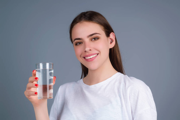 Girl drinking water, isolated on studio background. Young woman enjoy pure fresh mineral water. Thirsty woman hold glass aqua water. Healthy water to refreshment - Фото, изображение