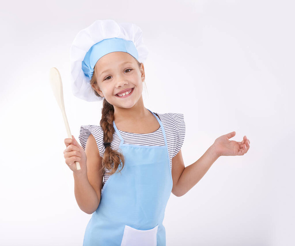 Вчимося готувати. Симпатична молода дівчина в одязі кухарів і вчиться пекти ізольовані на білому
 - Фото, зображення