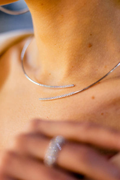 Primo piano di una collana con diamanti, diamanti e oro bianco sul delicato collo di una ragazza. Donna srands in gioielleria - Foto, immagini
