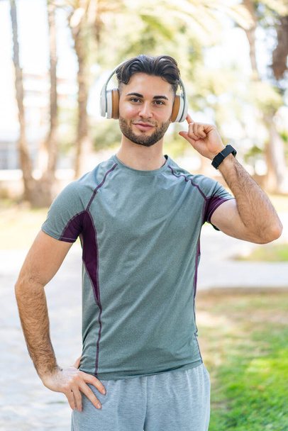 Man die buiten muziek luistert met een koptelefoon - Foto, afbeelding