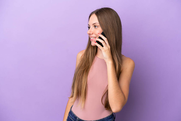 Nuori liettualainen nainen eristetty violetti tausta pitää keskustelun matkapuhelimen kanssa jonkun - Valokuva, kuva