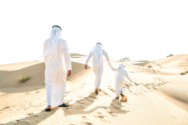 Three generation family making a safari in the desert of Dubai wearing white kandura outfit. Grandfather, son and grandson spending time together in the nature. - Foto, Imagem