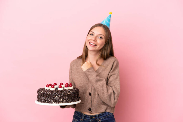 Young Lithuanian woman holding birthday cake isolated on pink background celebrating a victory - Photo, Image