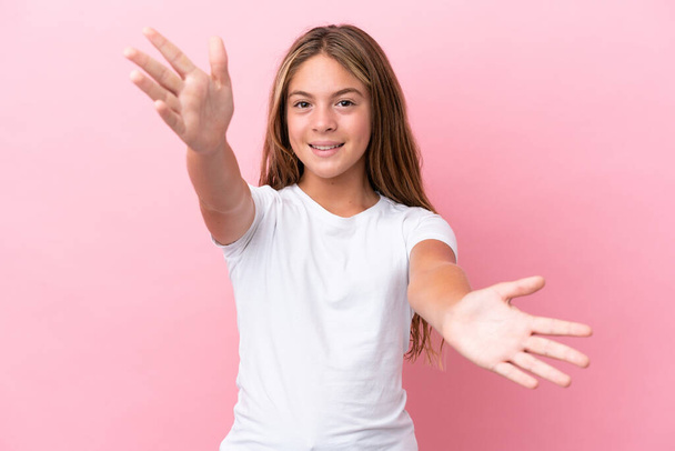 Little caucasian girl isolated on pink background presenting and inviting to come with hand - Foto, immagini